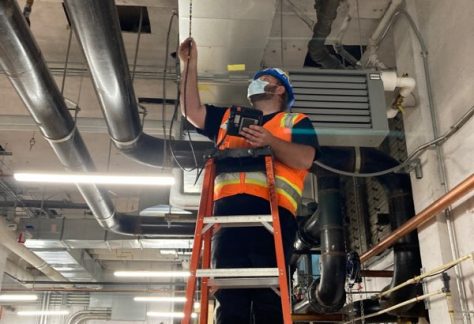 Sheet Metal Worker on ladder fixing air ducts